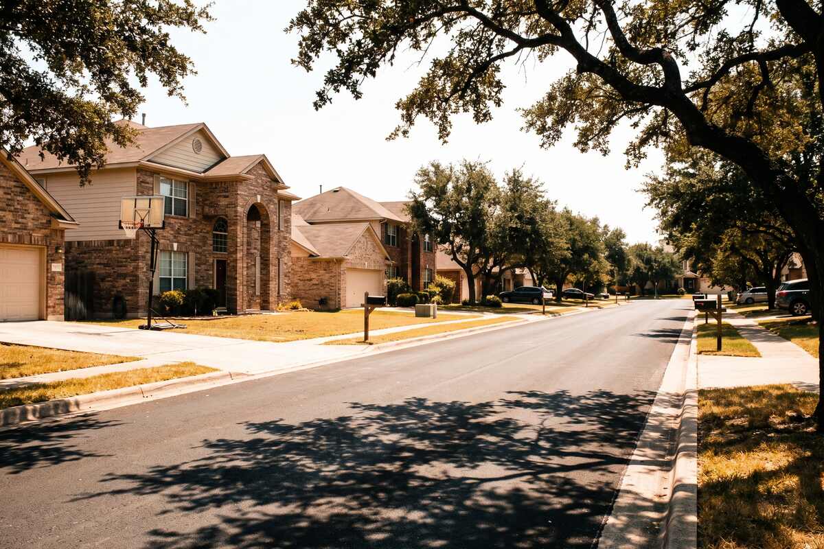 An established Cedar Park street of late 1990s two story brick homes shaded by mature live oaks.