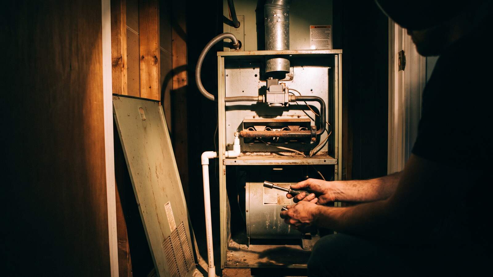 Gas furnace and air handler standing in a hallway closet with the flue, gas line and shutoff valve visible.