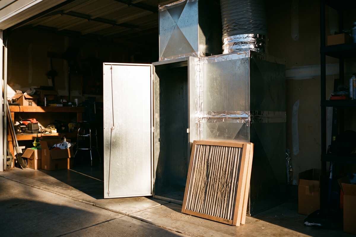 A four inch media filter cabinet mounted at the return plenum of an attic air handler with the door open.