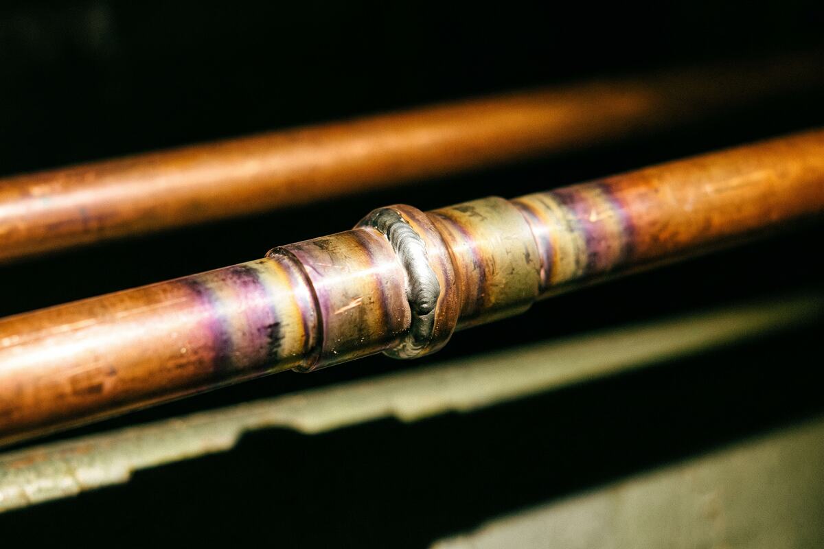 Brazed copper line set joints and a nitrogen regulator staged at an attic air handler during a changeout.